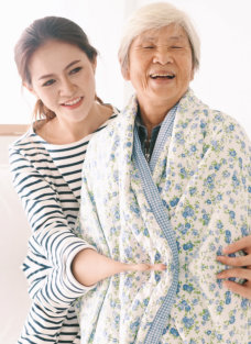 caregiver giving blanket to elder woman